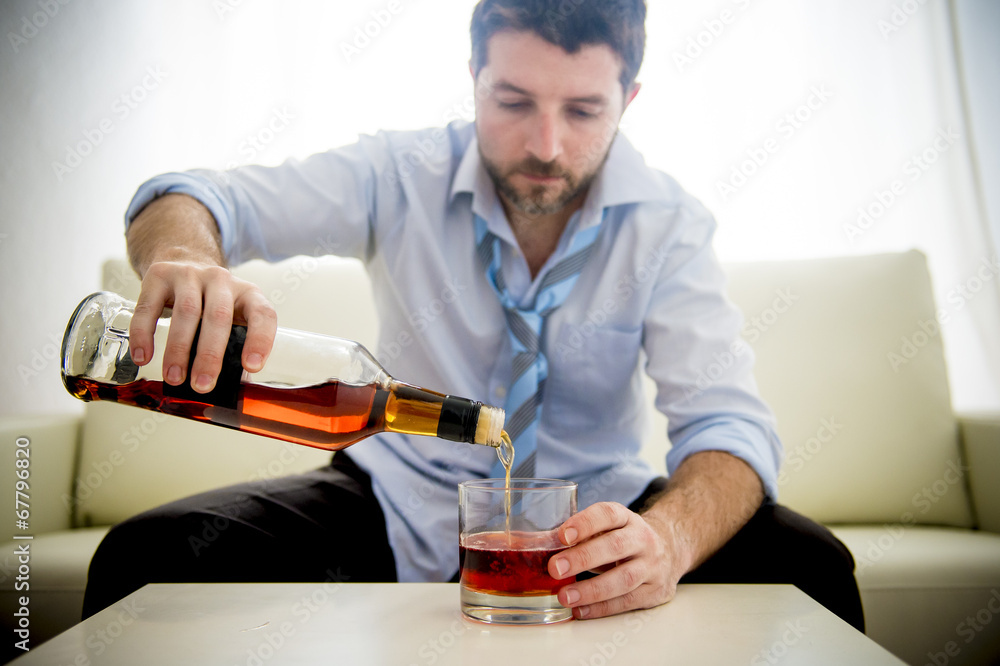 nk Businessman filling whiskey glass sitting on couch at home nk Businessman filling whiskey glass sitting on couch at home
