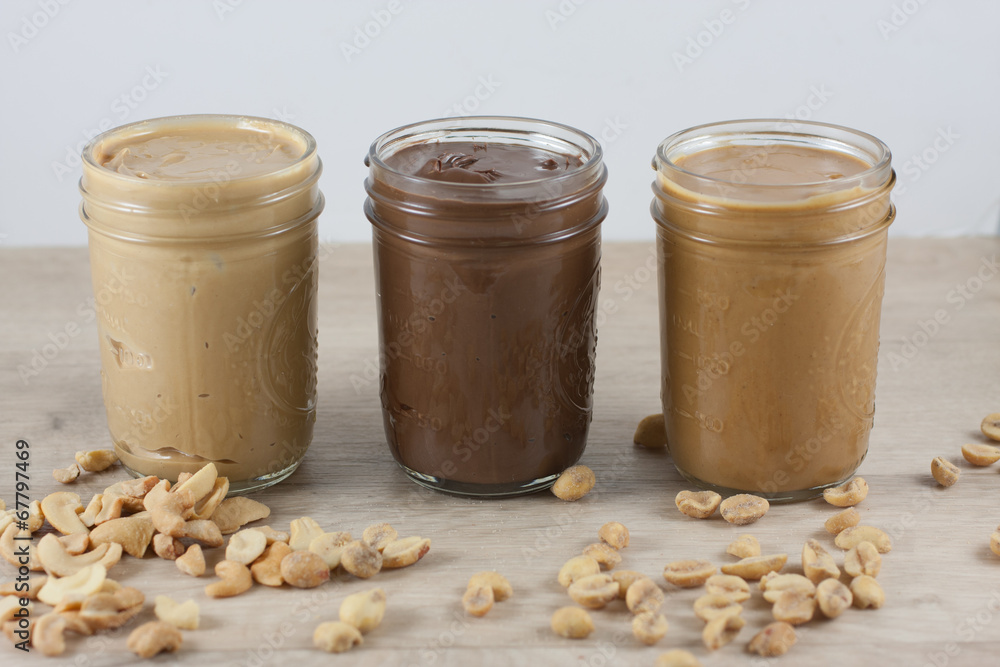 Peanut butter, hazlenut spread, and cashew butter on a table. Peanut butter, hazlenut spread, and cashew butter on a table.