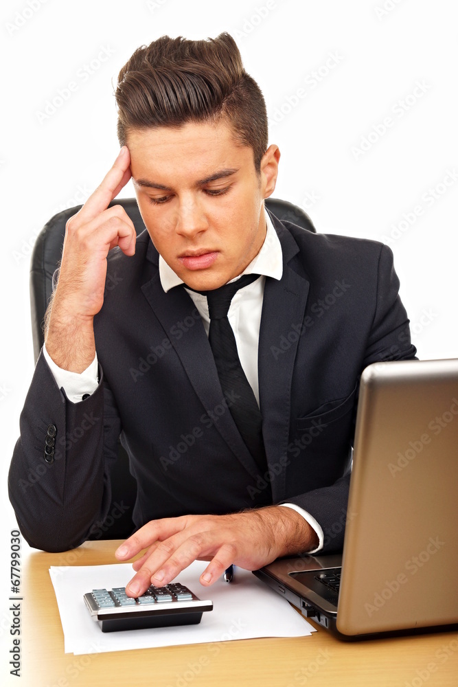 Thoughtful young man in suit counts on a calculator Thoughtful young man in suit counts on a calculator