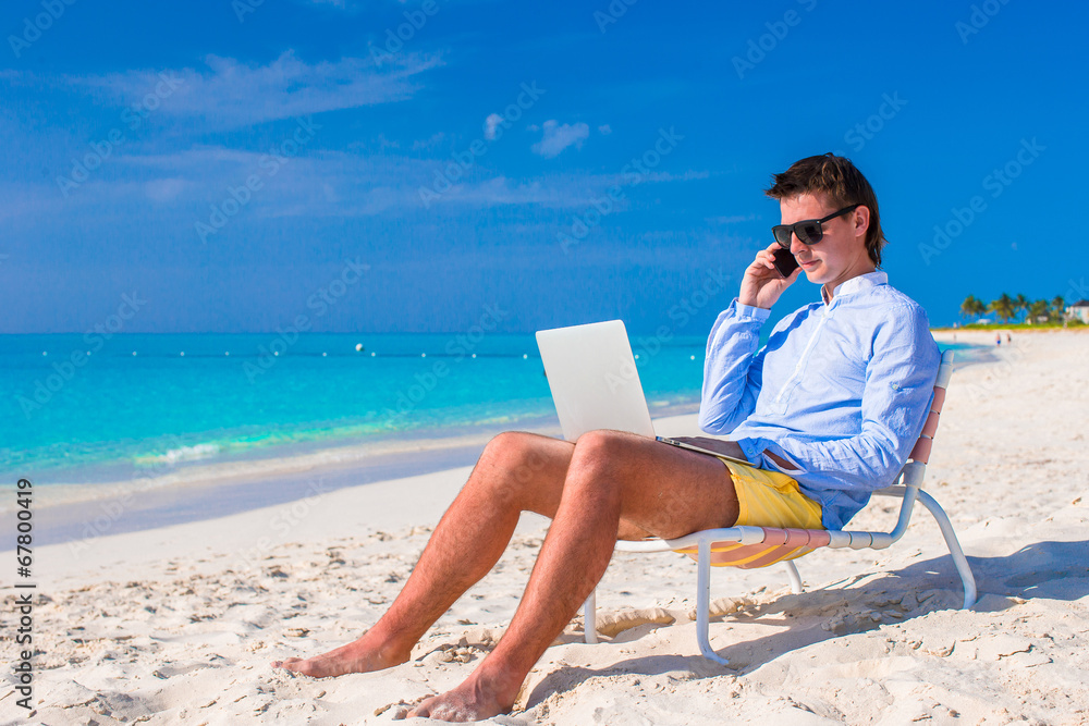 Young businessman using laptop on tropical beach