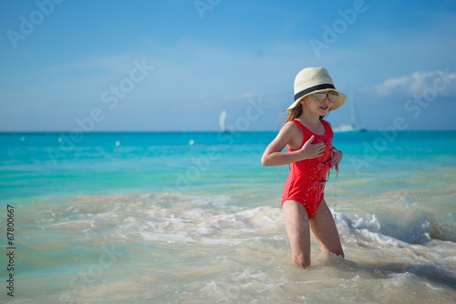 Happy little girl in hat on beach during summer vacation