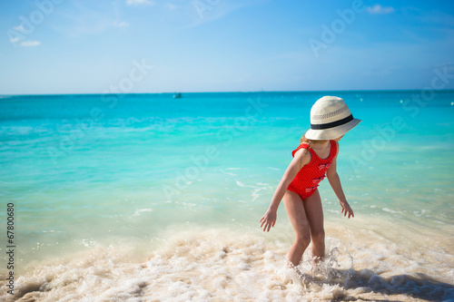 Adorable little girl playing in shallow water at exotic beach