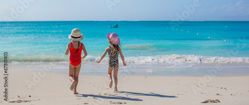 Back view of two happy little girls playing on white beach photo