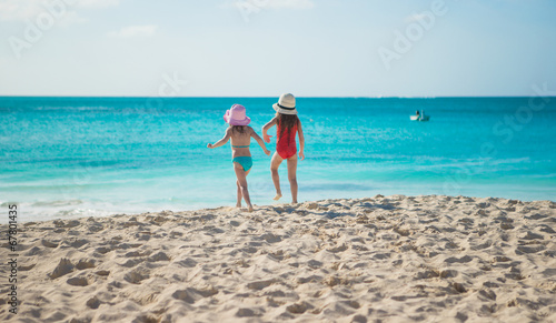 Little cute girls walking on white beach during vacation