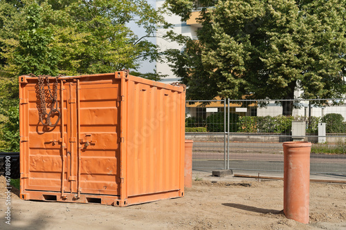 Ein oranger Werkzeugcontainer steht auf einer Strassenbaustelle