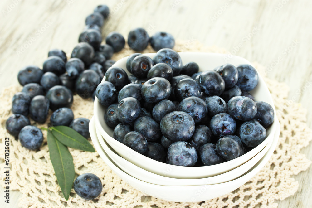 Blueberries in plates on napkin on wooden background Blueberries in plates on napkin on wooden background