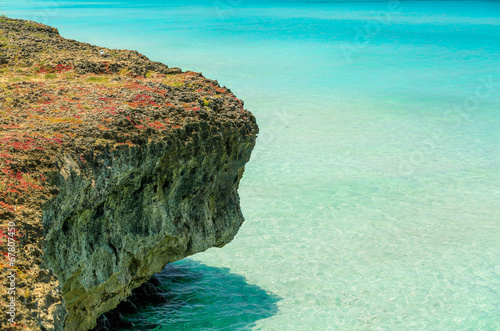 stone cliff standing in clear turquoise ocean water background photo