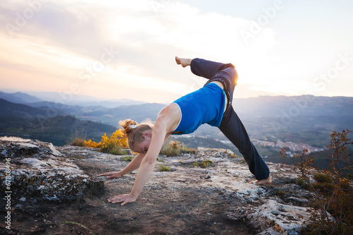 Young Caucasian woman working out on a rock against valley view
