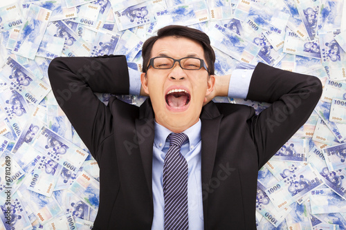 happy  business man lying on the stacks of new taiwan dollar photo