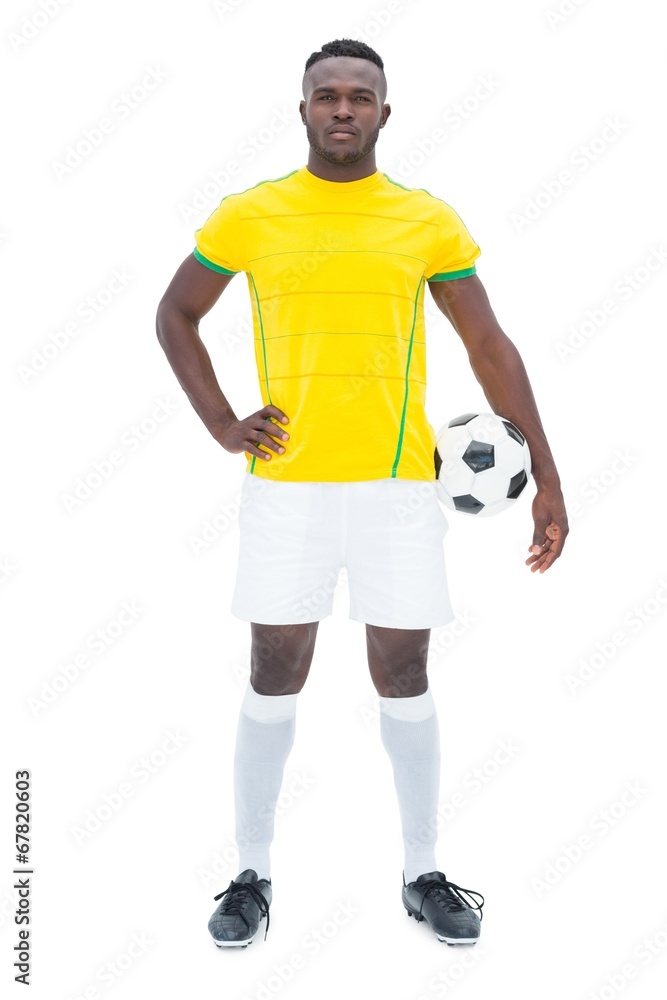 Football player in yellow standing with the ball