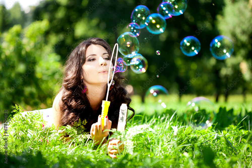 Woman and soap bubbles in park. Beautiful young girl lying on th Woman and soap bubbles in park. Beautiful young girl lying on th
