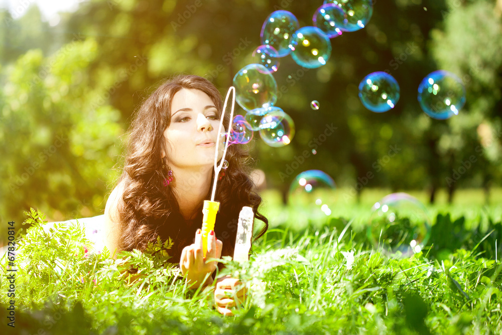Woman and soap bubbles in park. Beautiful young girl lying on th Woman and soap bubbles in park. Beautiful young girl lying on th