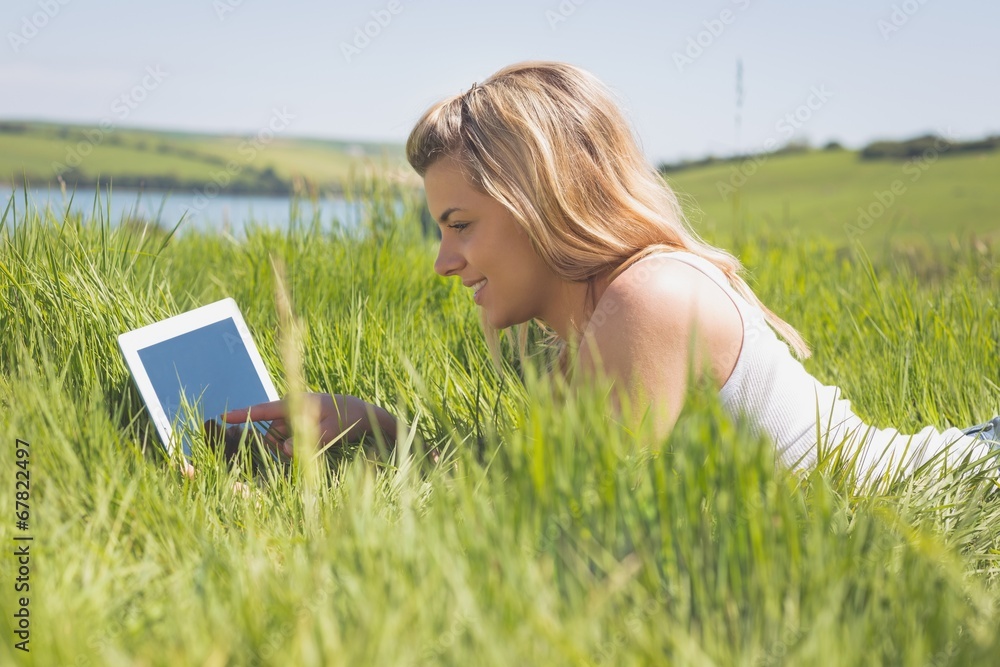 Pretty blonde lying on grass using her tablet Pretty blonde lying on grass using her tablet