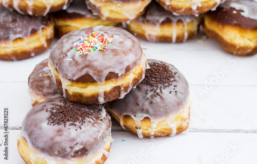 Stack of donuts with color glaze. Composition on white wooden bo