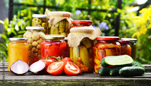 Fotografi Jars of pickled vegetables in the garden. Marinated food