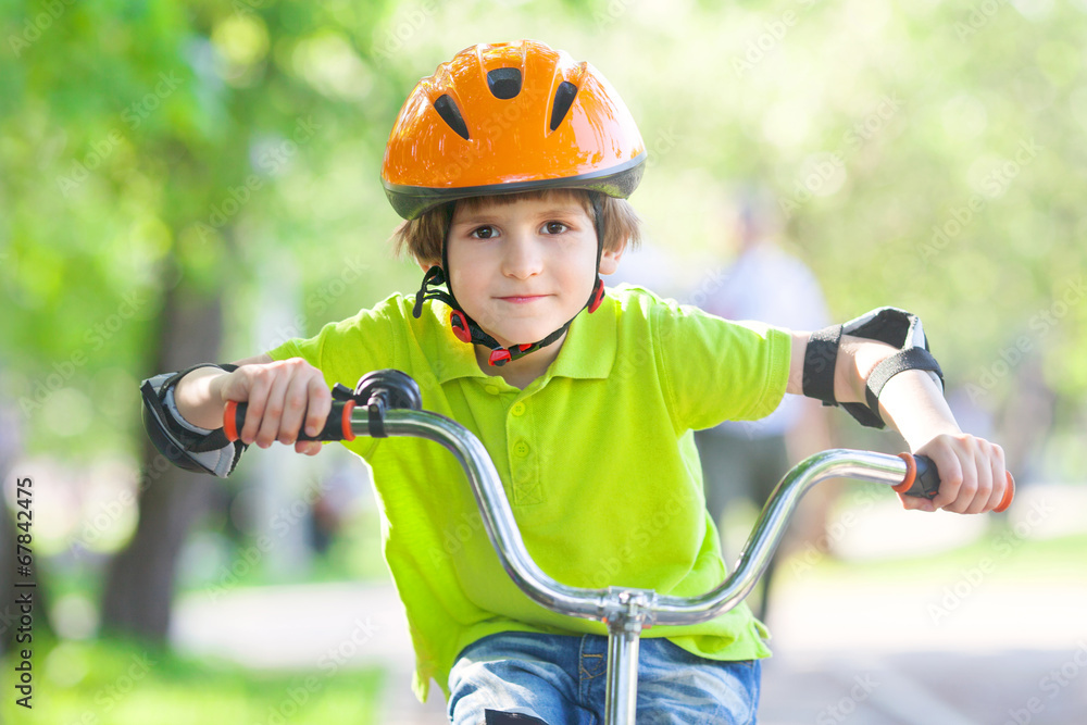 Naklejka premium The boy rides a bicycle in summer Park