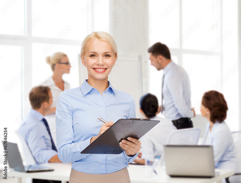 smiling businesswoman with clipboard and pen