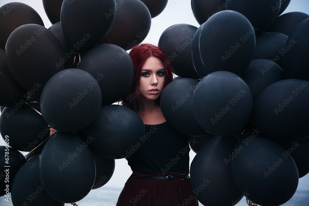 Obraz premium Beautiful girl walking with black balloons