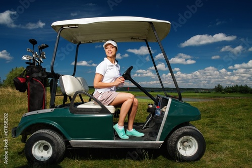 Young cheerful woman driving golf cart