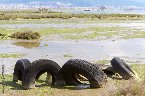 A discarded old tyre in a puddle of contaminated water photo