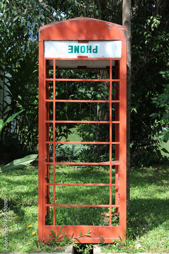 Old red telephone box in the park. © noomcm
