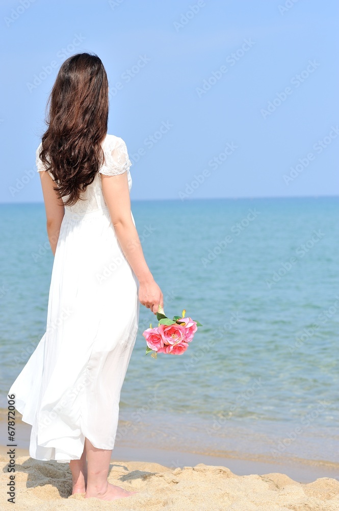 白いワンピースを着てピンクの花束を持って海に向かって立っている女性 Stock Photo Adobe Stock