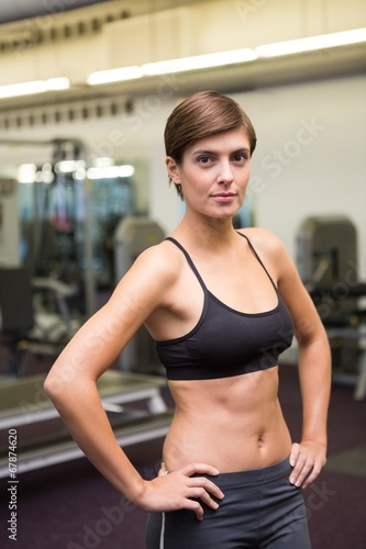 Fit brunette in black sports bra looking at camera