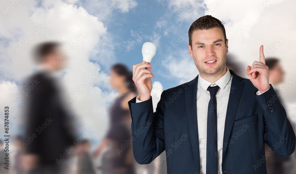 Composite image of businessman holding light bulb and pointing Composite image of businessman holding light bulb and pointing