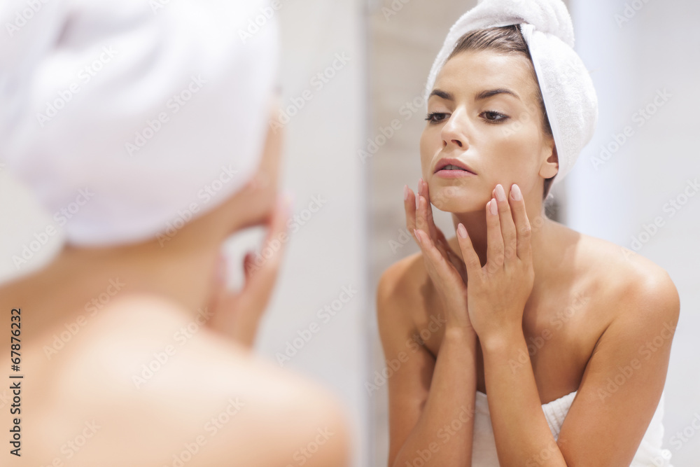 Woman looking on reflection in the mirror after shower Woman looking on reflection in the mirror after shower