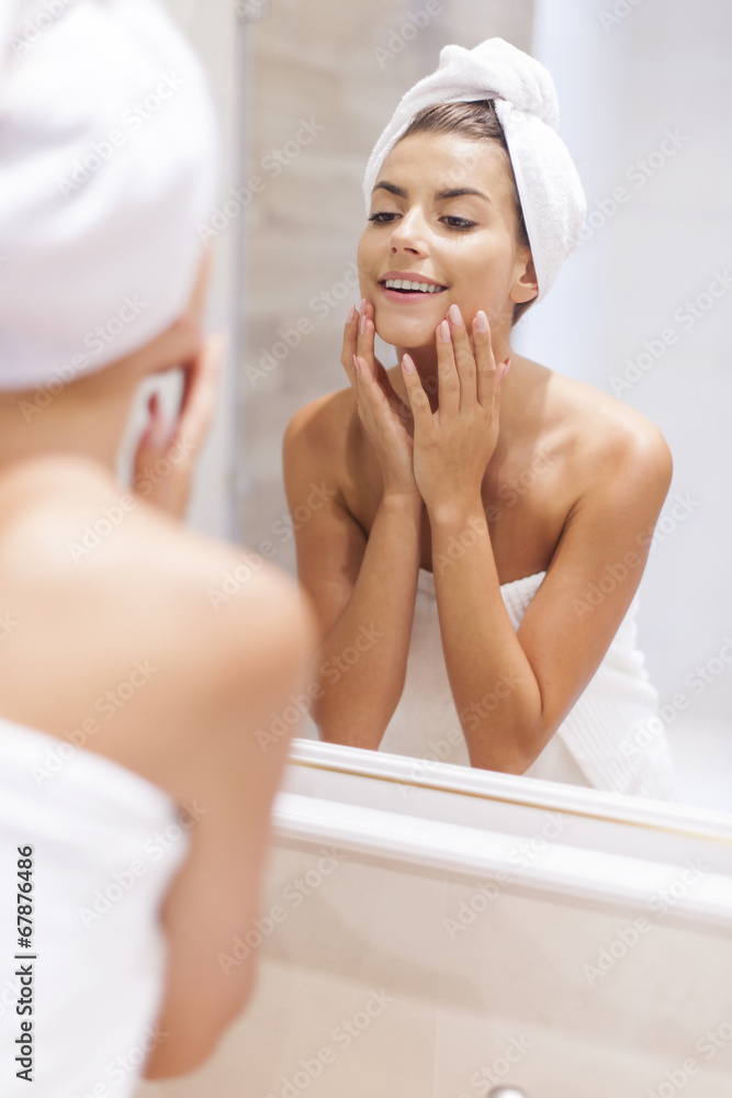 Woman looking on reflection in the mirror after shower Woman looking on reflection in the mirror after shower