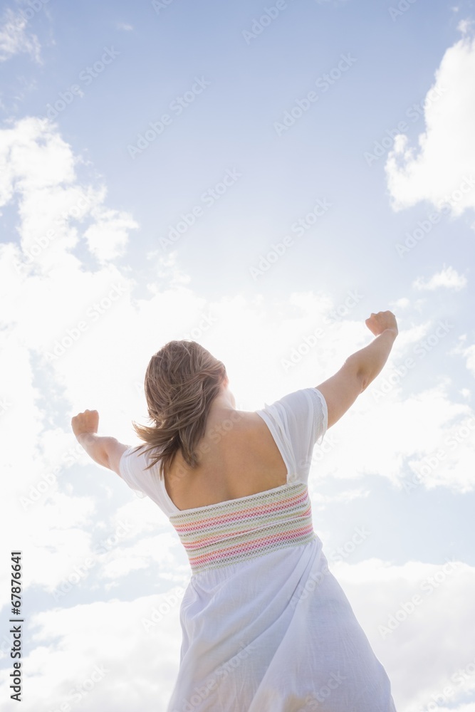 Woman with arms outstretched against blue sky and clouds Woman with arms outstretched against blue sky and clouds