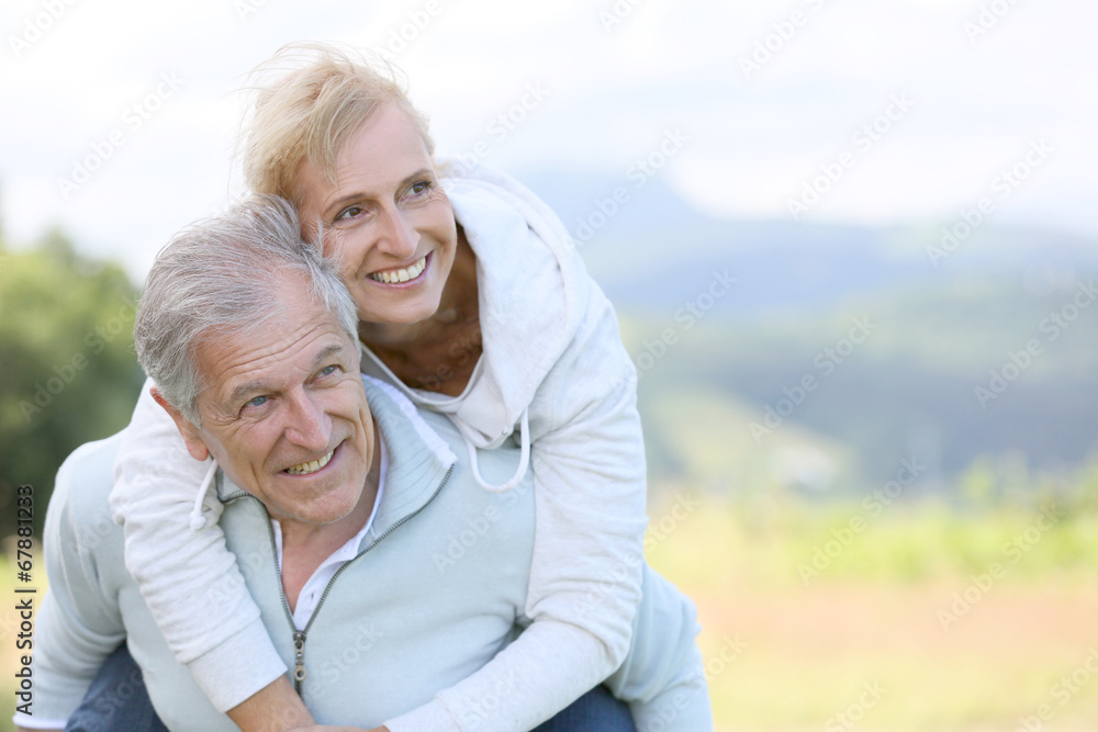 Senior man giving piggyback ride to woman