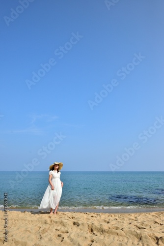白いワンピースと麦わら帽子を被ったアジア人の美しい女性と夏の海