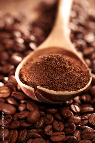 grated coffee in spoon on roasted coffee beans background