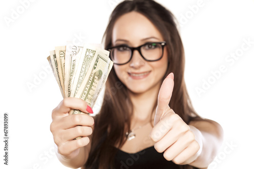 woman holding a wad of cash in hand and showing thumbs up