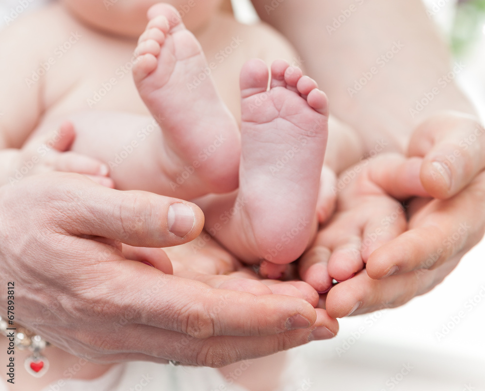 Mother and father gently hold baby legs in hands Mother and father gently hold baby legs in hands