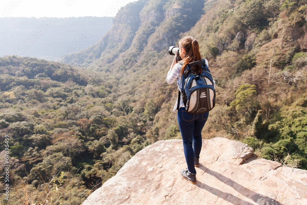 Obraz premium young woman taking photos on top of mountain