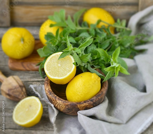 ripe organic lemons in a and fresh mint on a wooden background