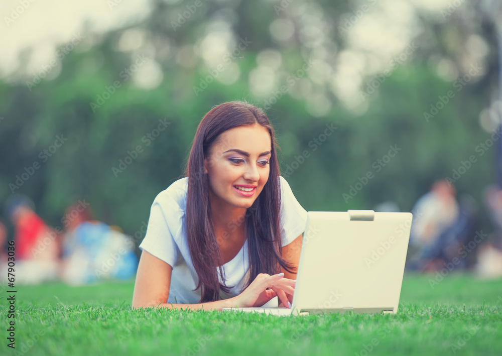 Brunette girl with notebook on green grass in the park. Brunette girl with notebook on green grass in the park.
