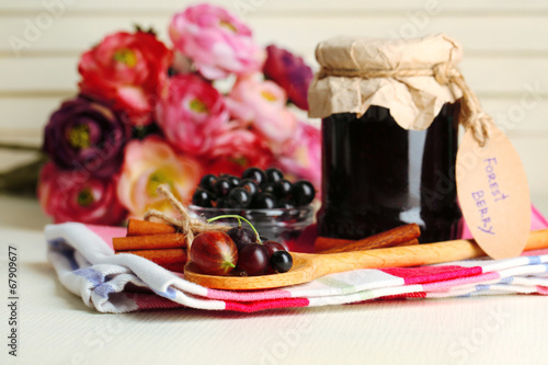 Ripe blackcurrants in bowl and glass jar with tasty jam