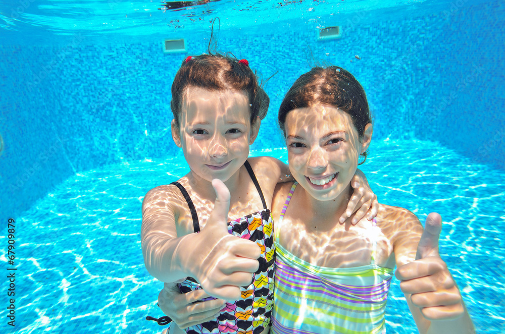 Happy active kids play underwater in swimming pool