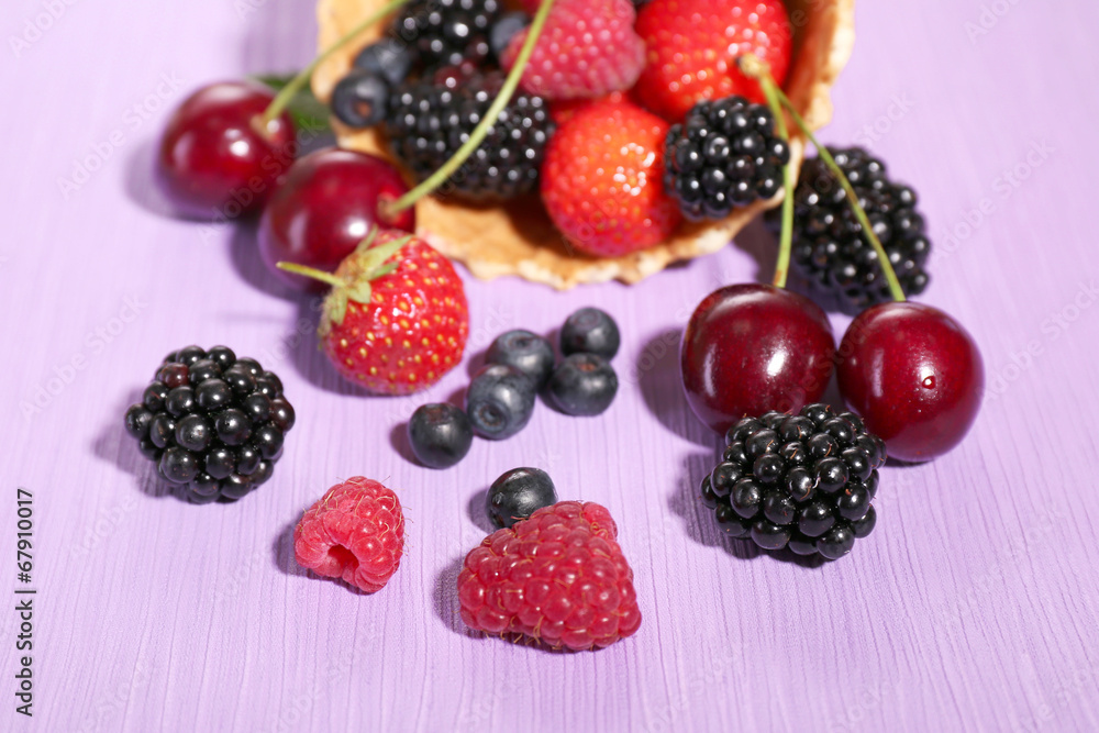 Different ripe berries in sugar cone, on purple background Different ripe berries in sugar cone, on purple background