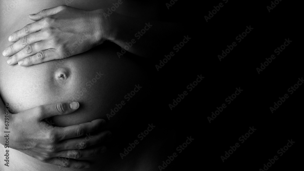 Expectant mother holding her belly, in low-key - obrazy, fototapety, plakaty 