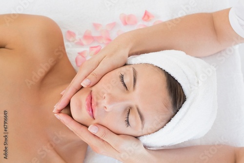 Attractive young woman receiving facial massage at spa center