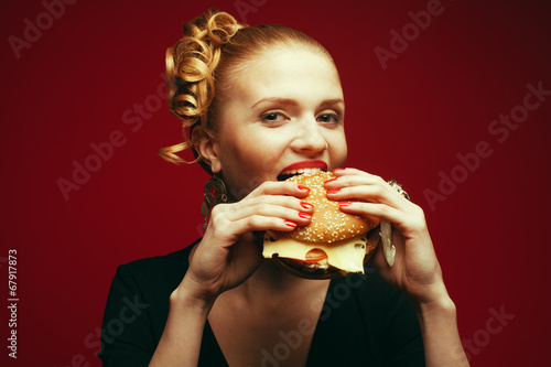 Fashion & Gluttony Concept. Rred-haired model eating burger