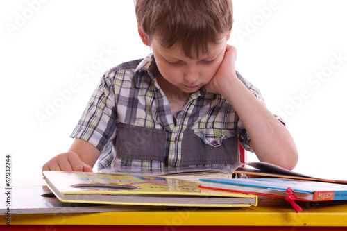 Junge sitzt am Schreibtisch und liest Bücher