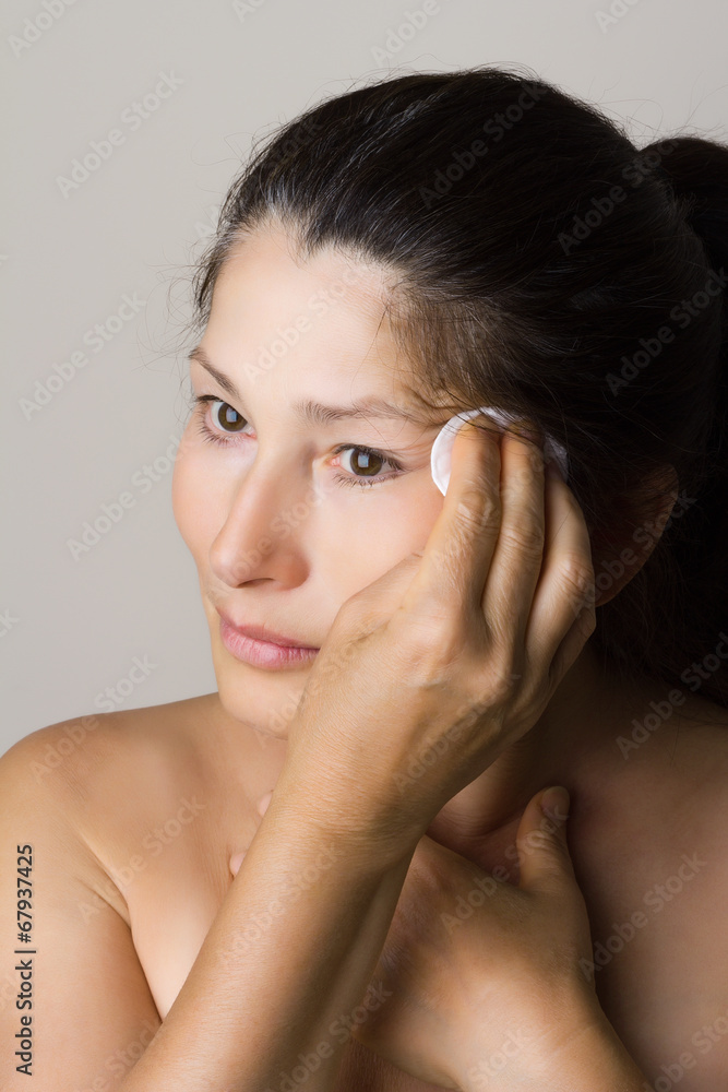 Asian woman clean face with lotion and cotton pad Asian woman clean face with lotion and cotton pad