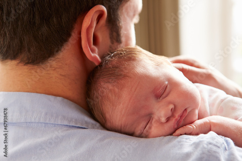 Father At Home With Sleeping Newborn Baby Daughter photo