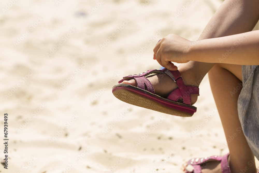 LIttle girl putting her sandals after playing in a sand pit Photos