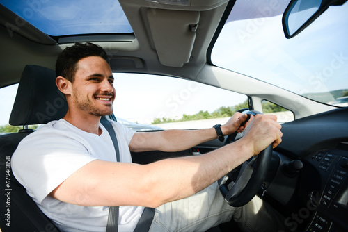 happy handsome young man driving his new car on highway photo